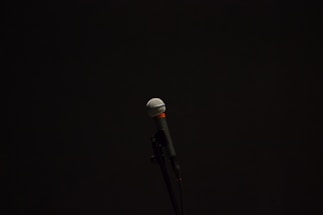 A sleek microphone on a dimly lit stage with soft spotlight.