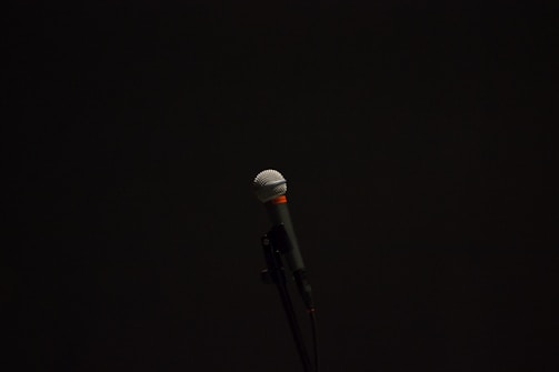 A sleek black and silver microphone glowing softly under purple stage lights.