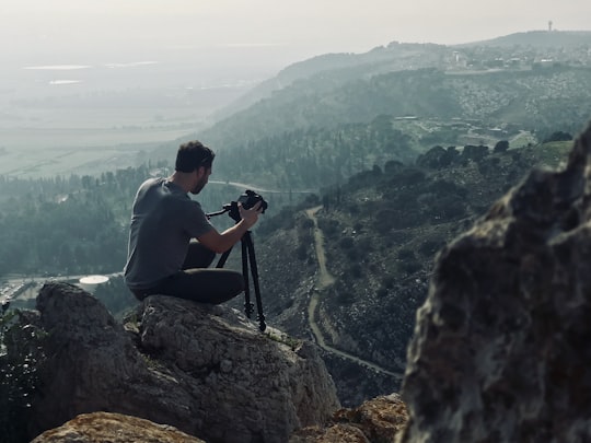 man sitting on rock using camera in Mount Precipice Israel