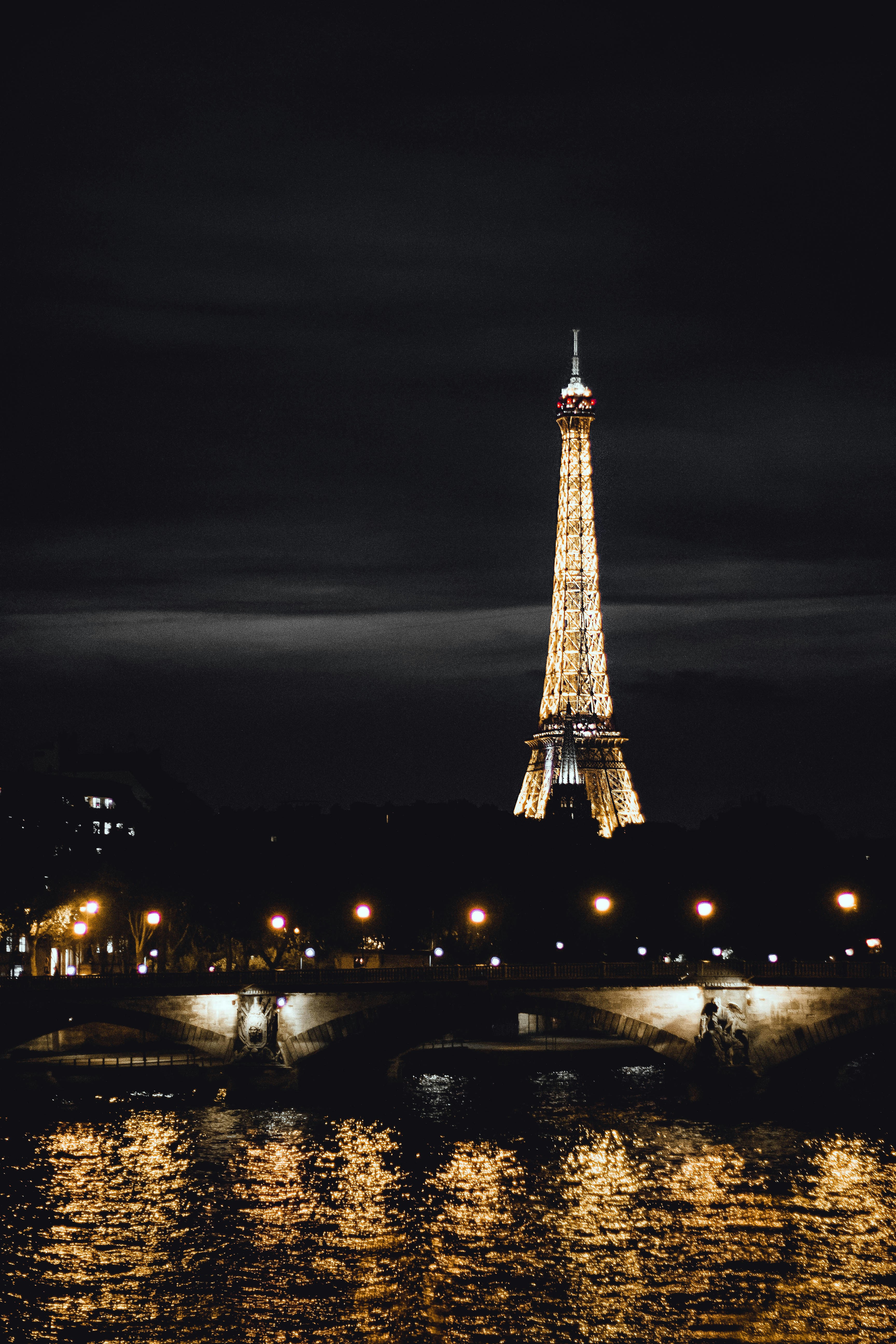 Iconic Eiffel Tower at dusk with warm golden lights reflected on the Seine River in Paris