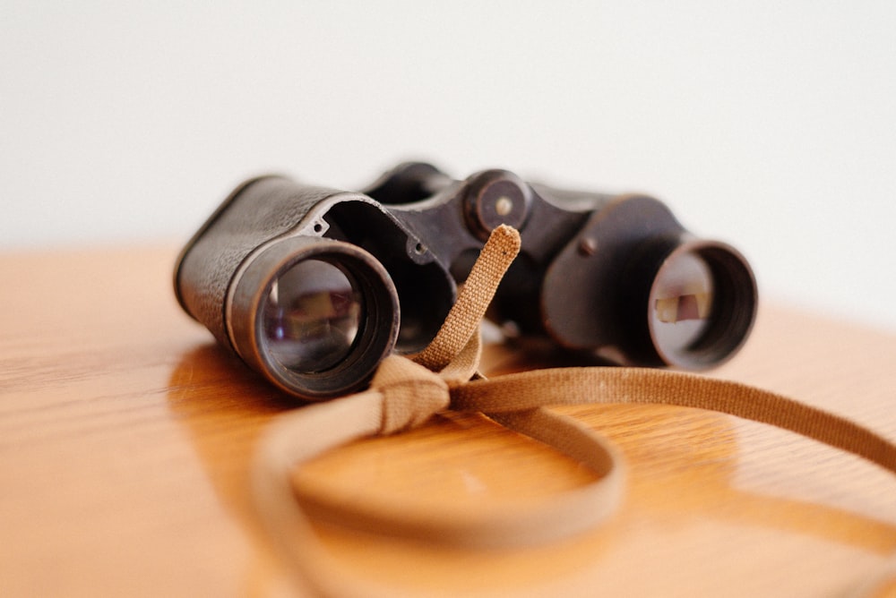closeup photo of binoculars on brown wooden surface