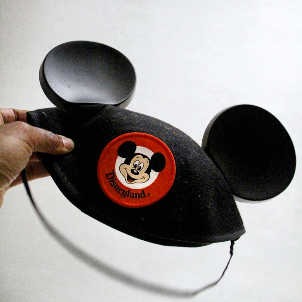 person holding Mickey Mouse cap