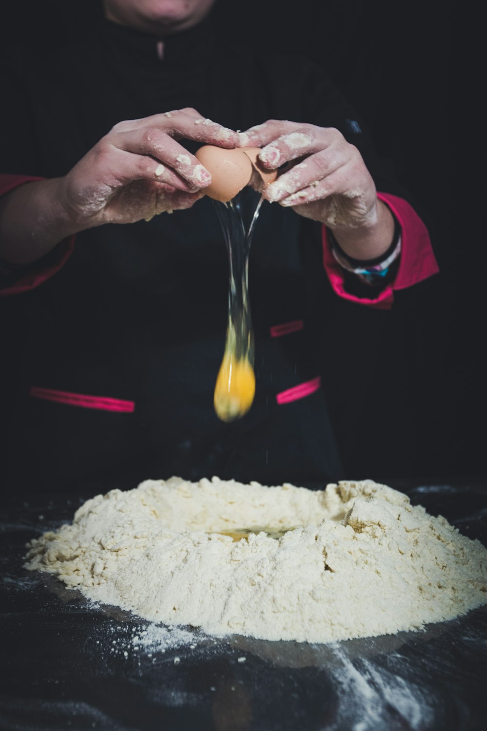 man pouring egg on flour