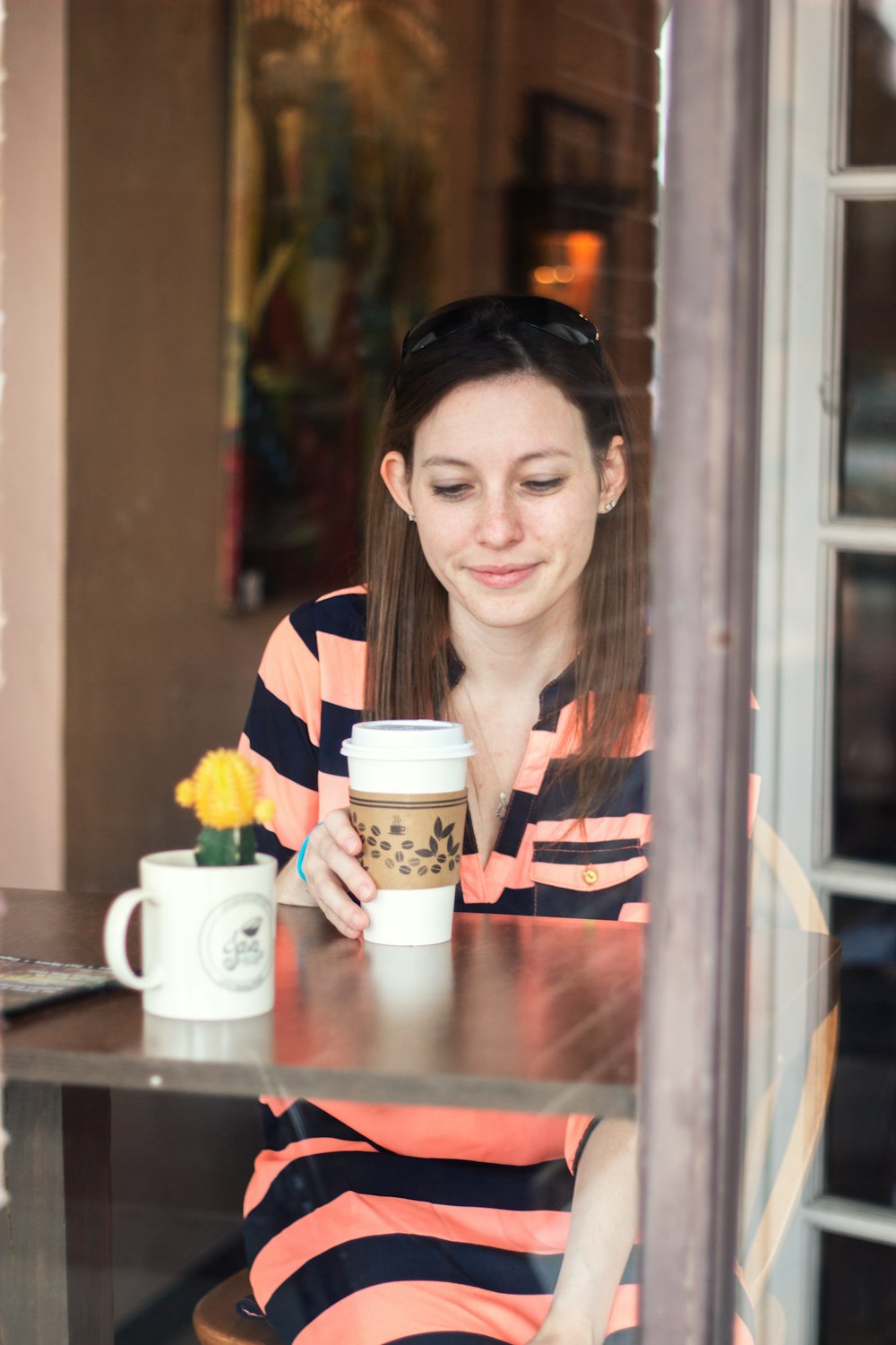 woman sitting down at table looking at cup in hand