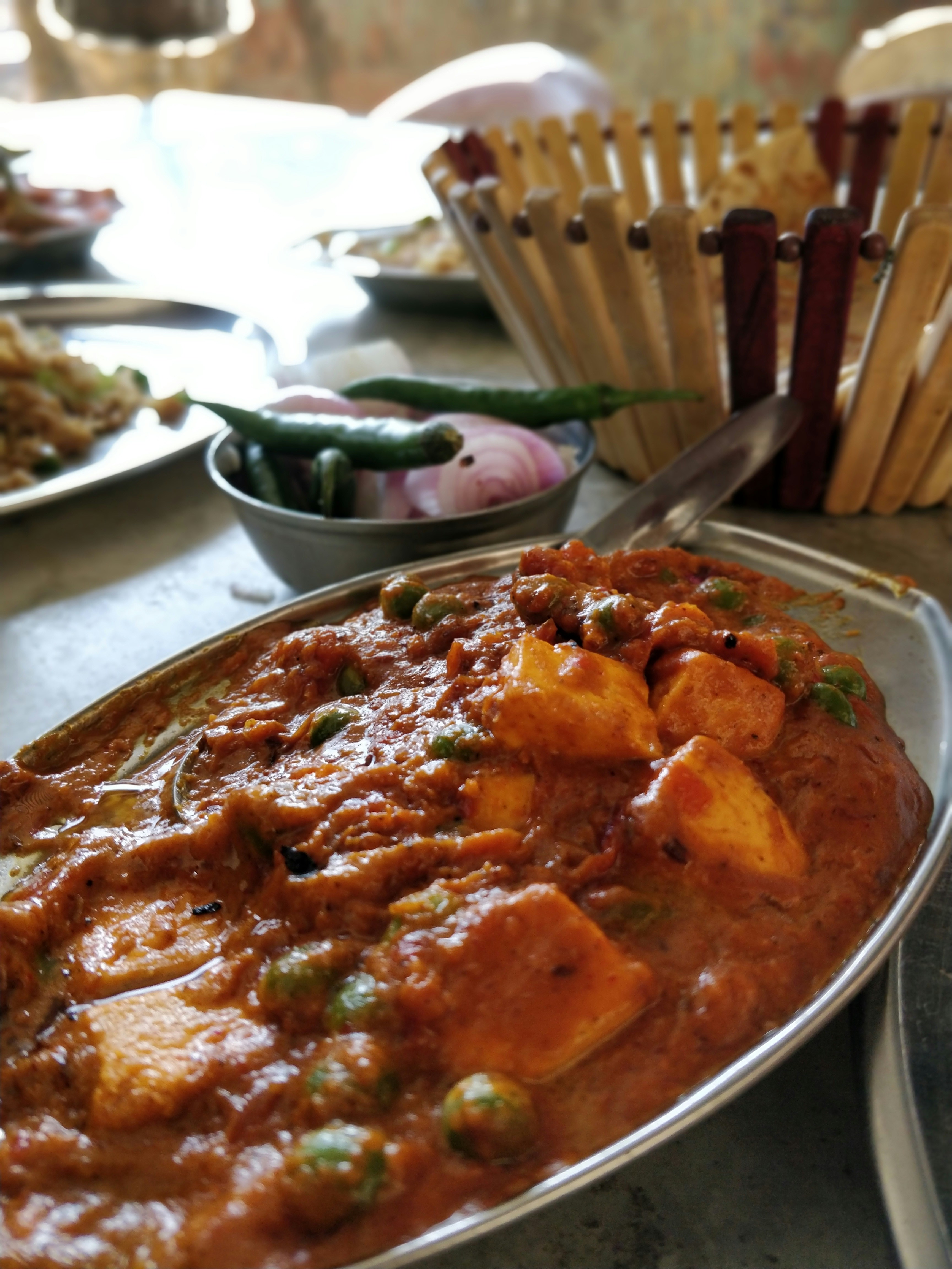 Paneer butter masala in ceramic bowl, dark background, warm restaurant lighting