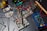 A collection of electronic components and test equipment spread across a table. There are breadboards with numerous colorful wires connected, a multimeter, and various test tubes in the background. The setup suggests a workbench for electronics or a science experiment.
