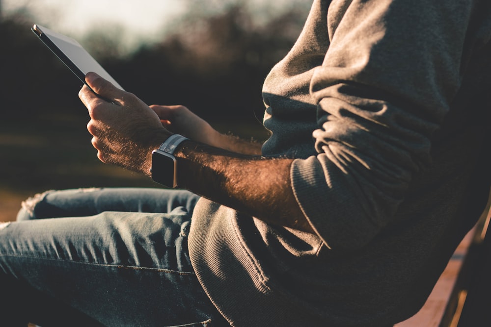 person sitting on chair using tablet