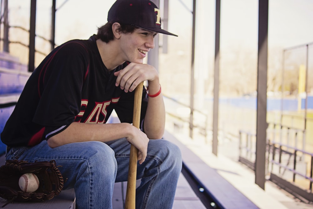 man sitting on bench holding baseball bat