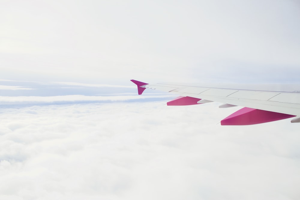 white and pink plane flying during daytime photography