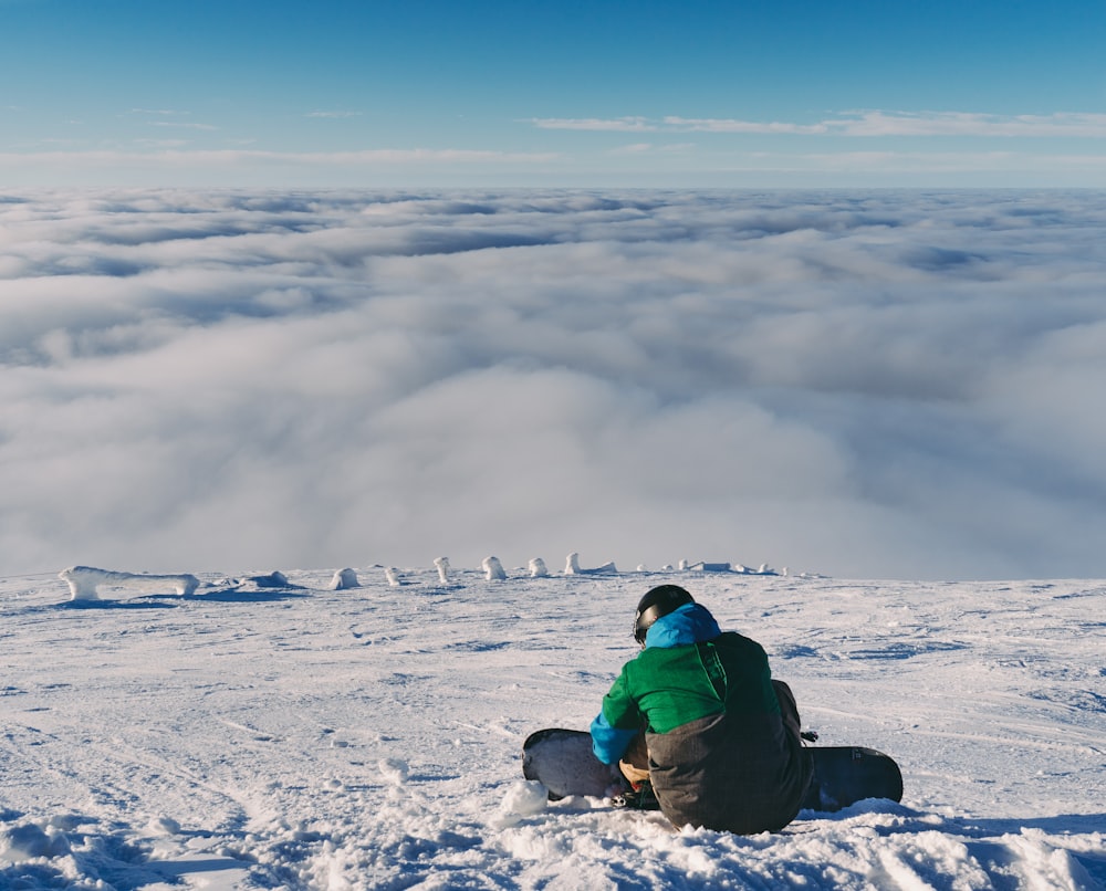 person holding snowboard while sitting on snow