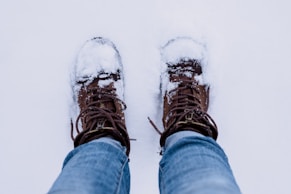 person wearing brown leather boots converted by snow