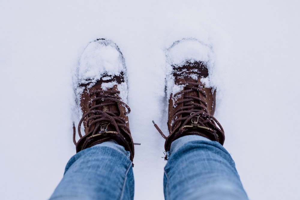 person wearing brown leather boots converted by snow