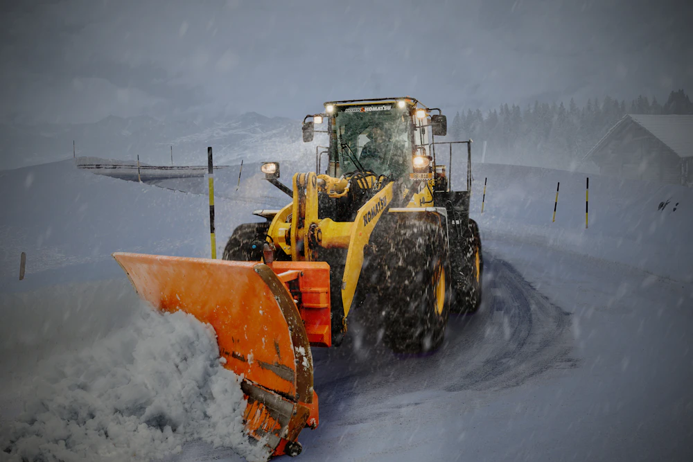 Yellow and orange snow plow on a snowy road