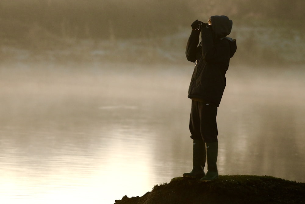 man on cliff looking at binoculars