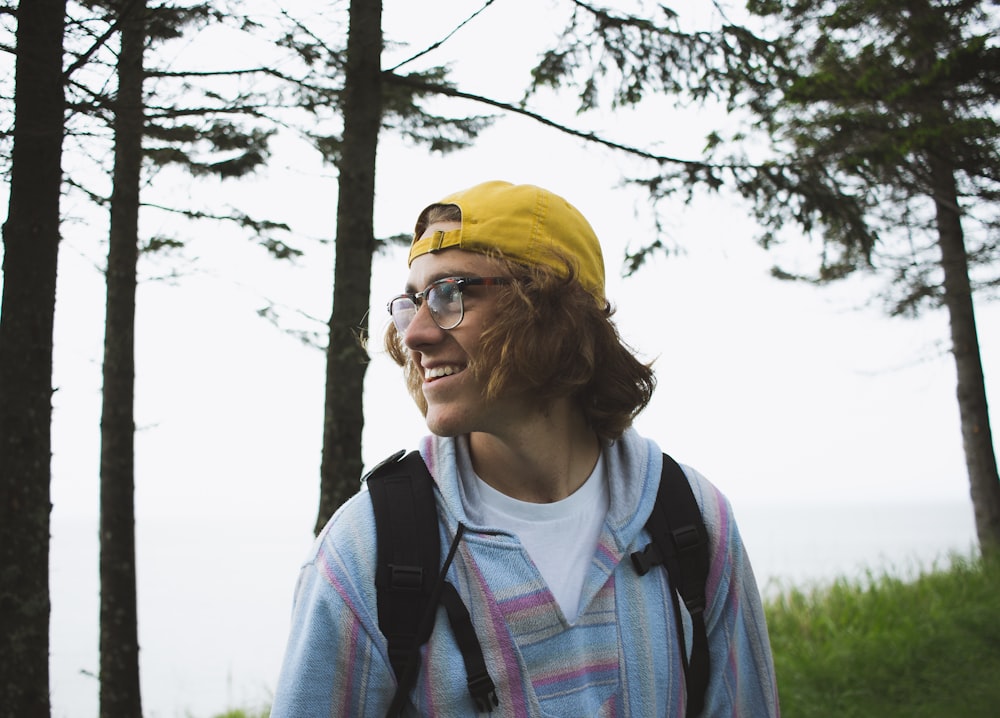 man in yellow cap standing in middle of trees