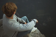 man sitting on rock near cliff