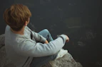 man sitting on rock near cliff