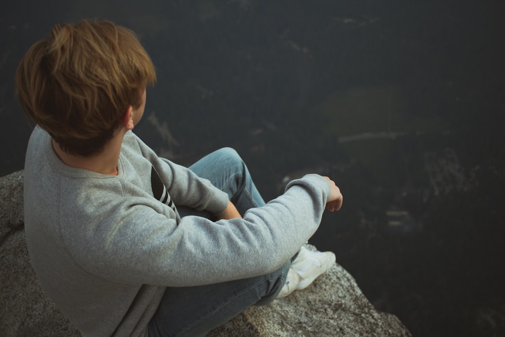 Hombre sentado en la roca cerca de un acantilado