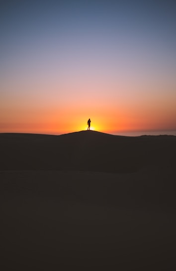 silhouette of person standing on hill