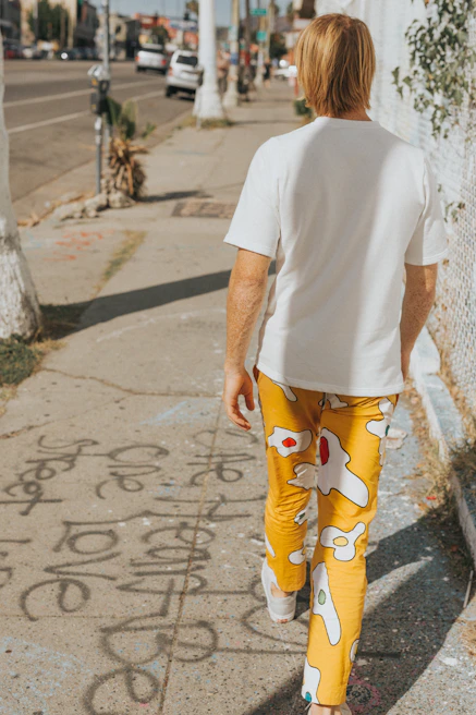 Model wearing a relaxed-fit, colorful shirt walking through a sunny urban street