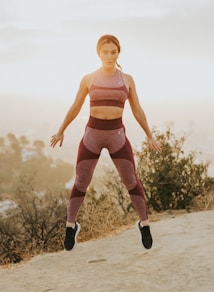 woman jumping above gray sand