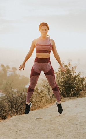 woman jumping above gray sand