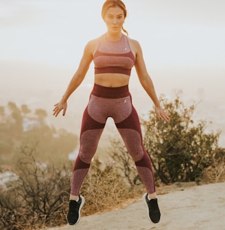 woman jumping above gray sand