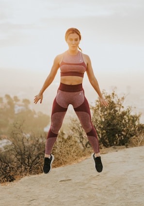 woman jumping above gray sand