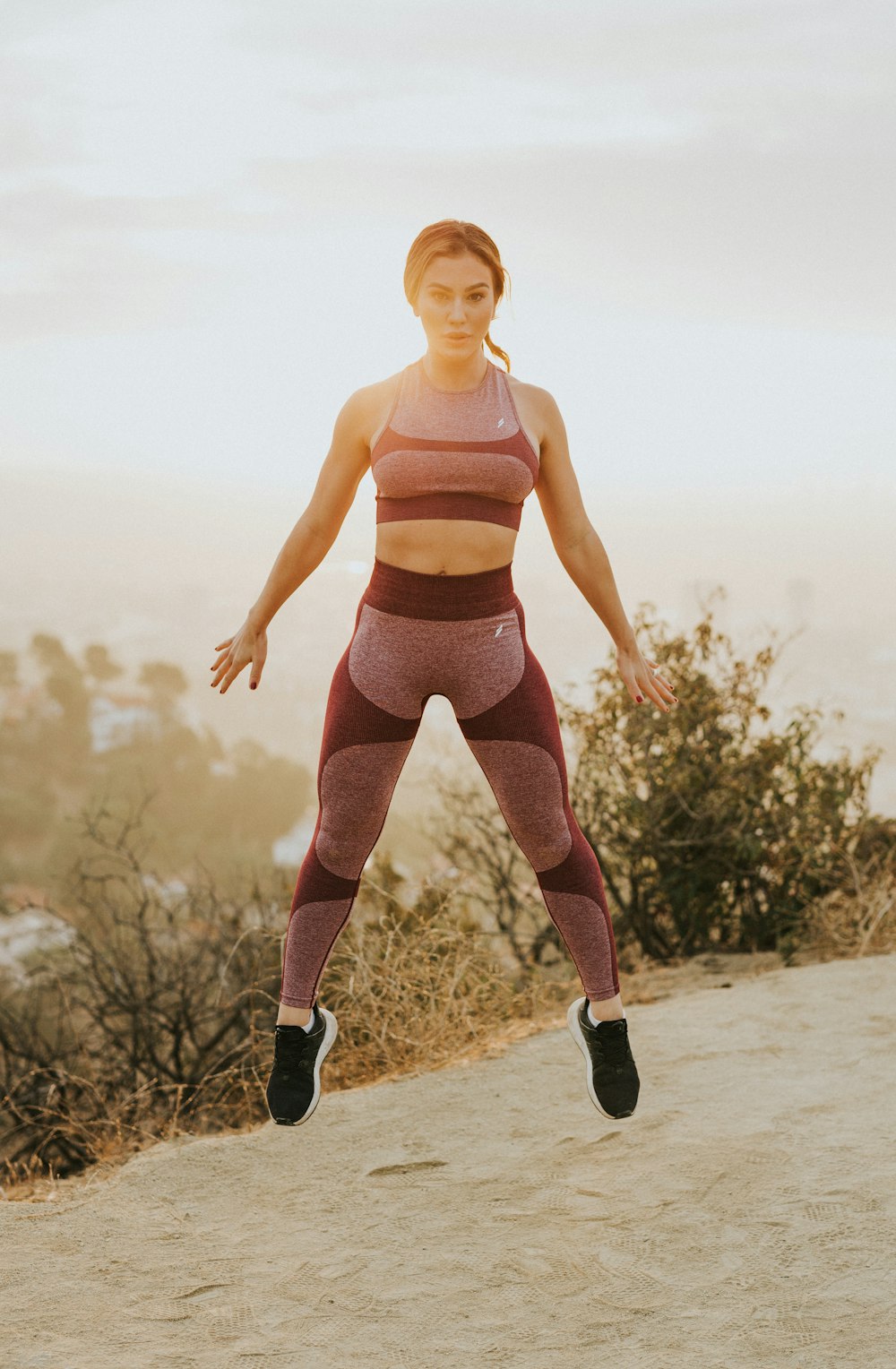 woman jumping above gray sand