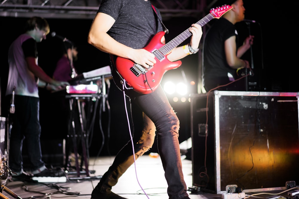 man playing a red electric guiitar