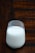 A glass of fresh milk with a rustic wooden background and a few farm elements like hay and a milk jug.