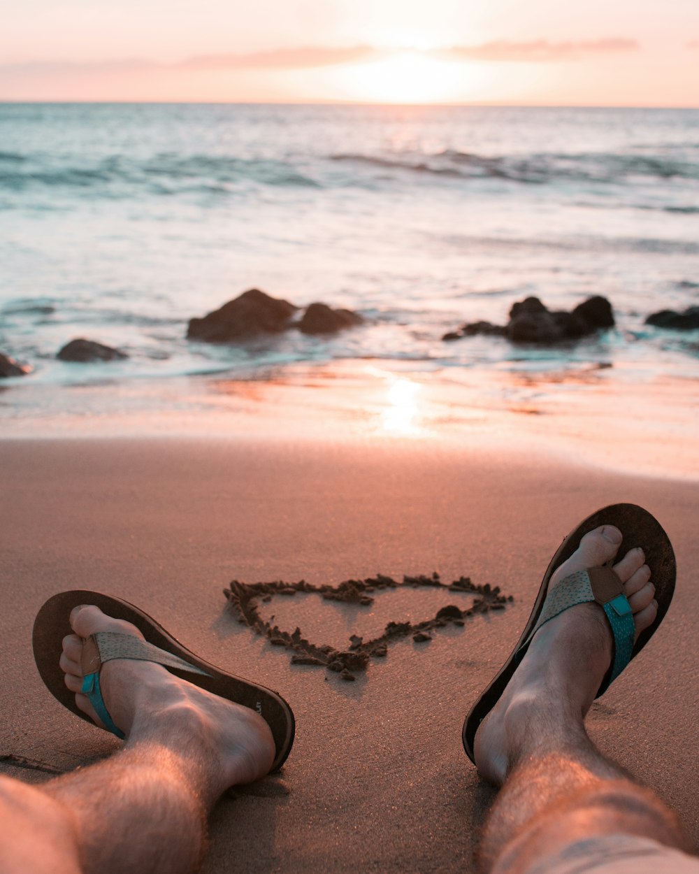 person sitting on sand near body of water