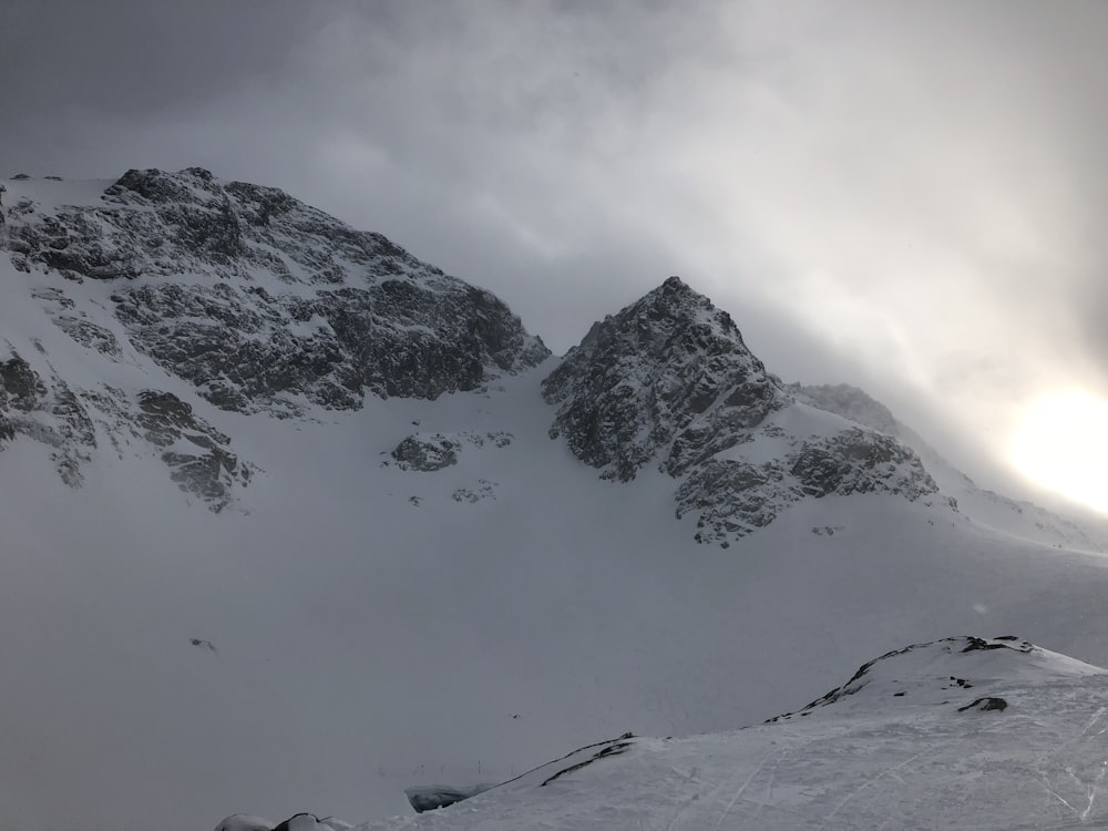 montanha coberta de neve sob céu nublado durante o dia