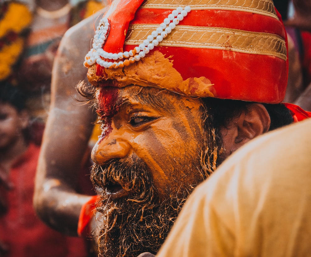 man in gold and red striped head dress with painted face