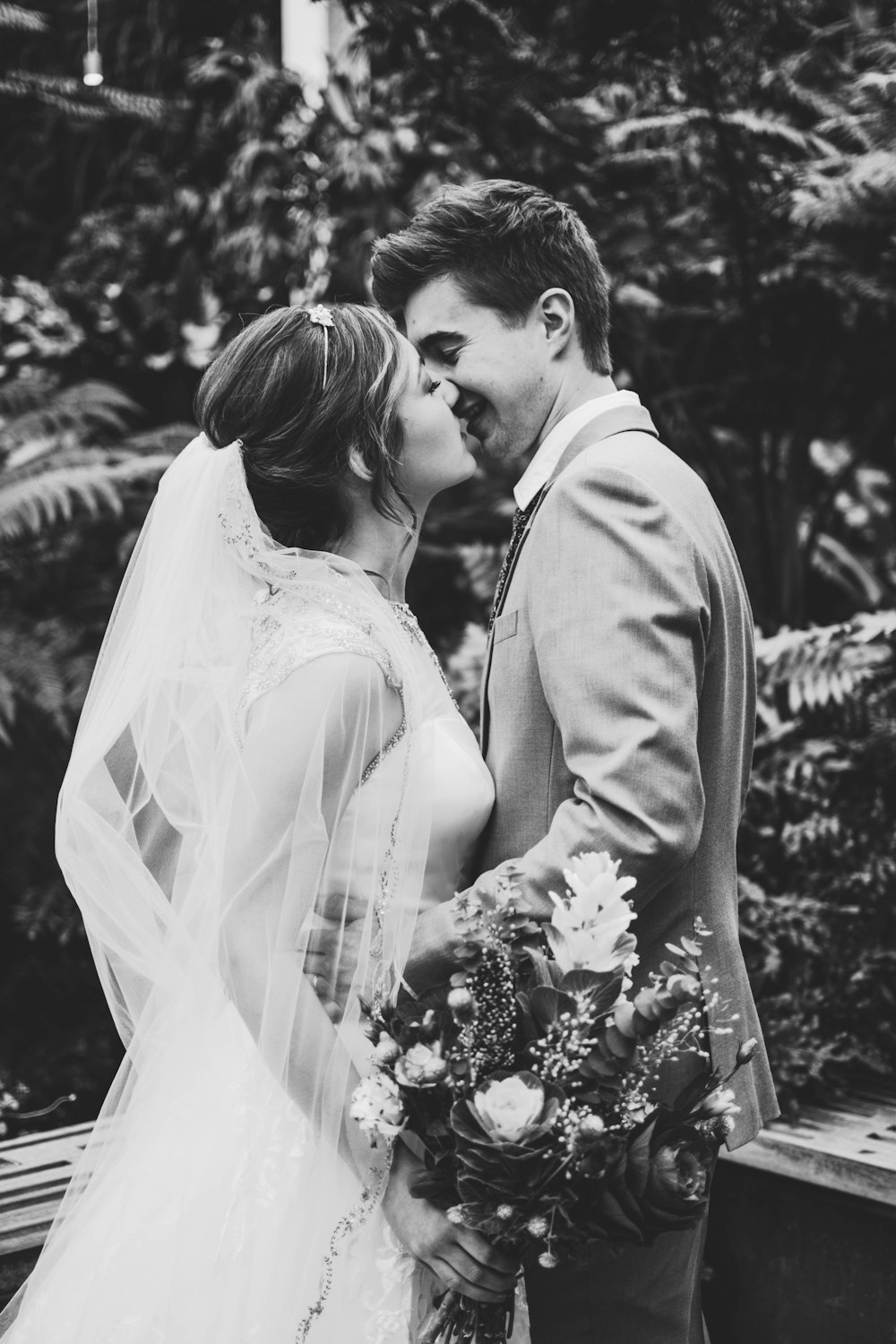 Foto en escala de grises de parejas besándose y usando vestido de novia