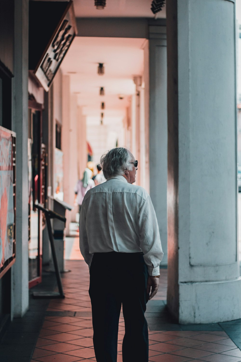 man wearing white dress shirt walking on hallway