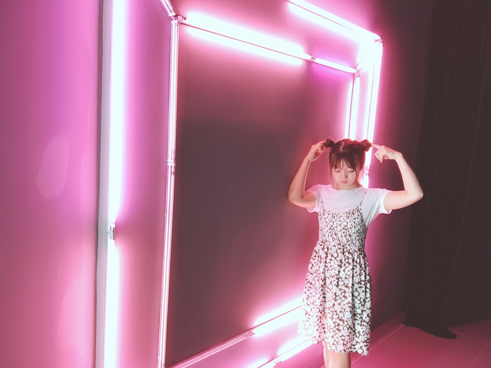 woman in dress standing near pink neon lights