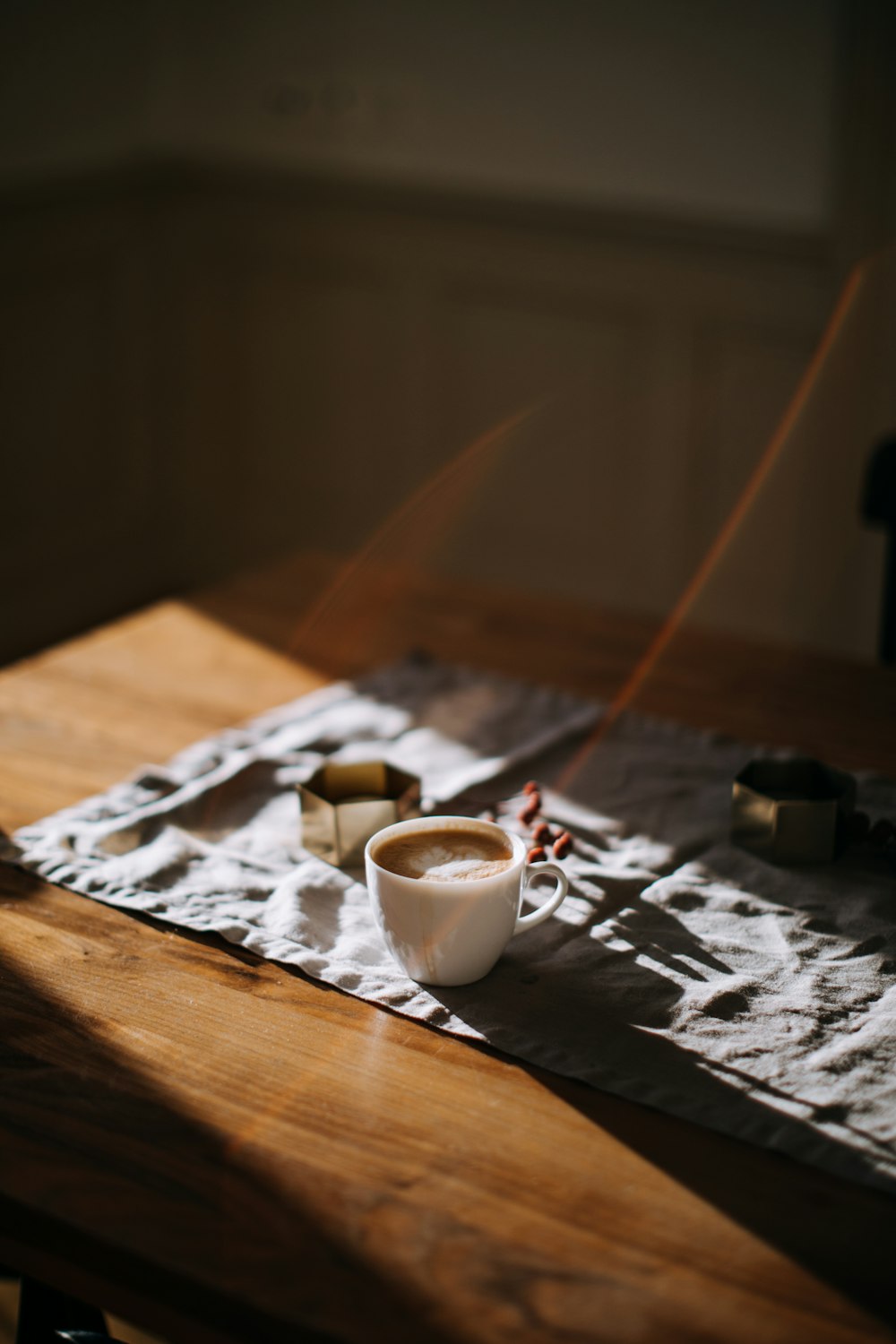 coffee mug on top of tablecloth beside ashtray
