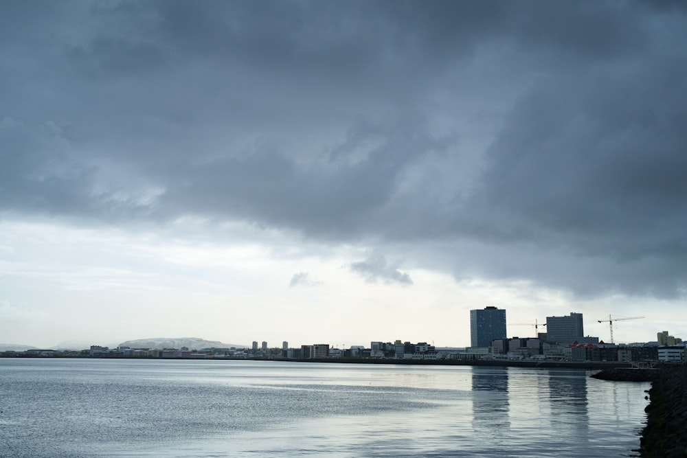 body of water near city buildings under cloudy sky during daytime