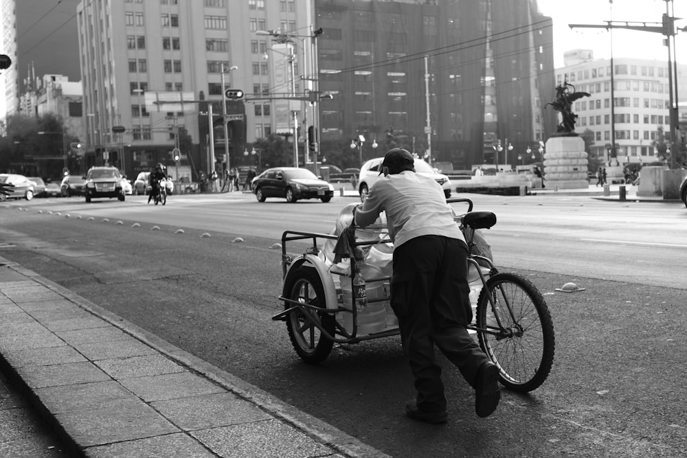 homme en chemise blanche et pantalon noir chevauchant sur un vélo en photographie en niveaux de gris