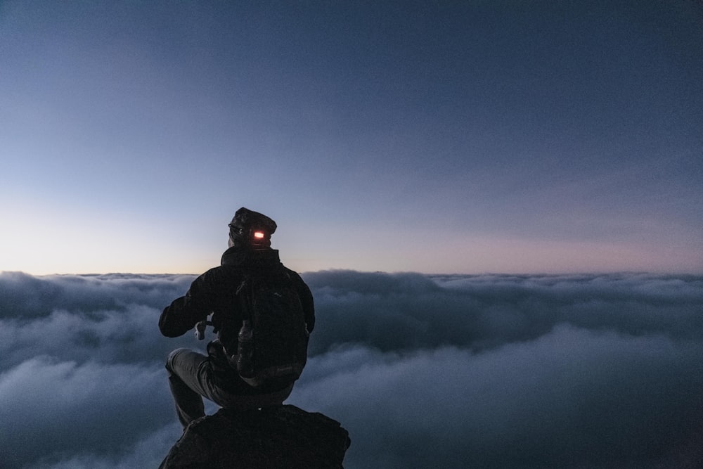 hombre sentado en la cima de la montaña