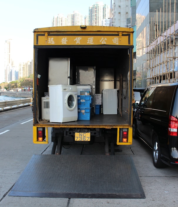white front-load washer in yellow delivery truck