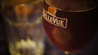 Close-up of a cold glass of Heller beer with a guitar and a concert stage blurred in the background.