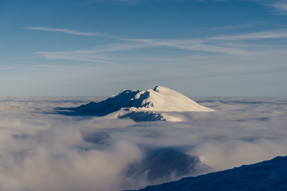 weißer Berg umgeben von grauen Wolken unter blauem Himmel