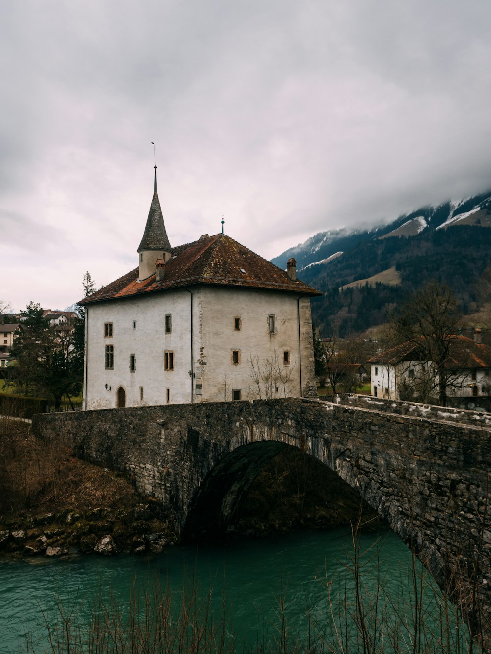 landscape photography of white concrete house near bridge under cloudy sky