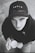A young person gazes upward while holding a cup. They are wearing a black cap with the word 'YOUTH' on it and a dark hoodie. The image is in black and white, contributing to a nostalgic or contemplative atmosphere.