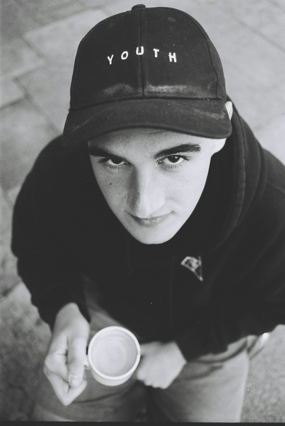 Photographie en niveaux de gris d’un homme tenant une tasse