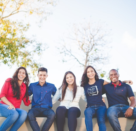 group of people sitting on bench near trees duting daytime