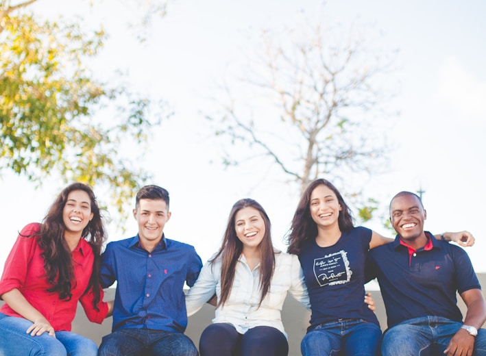 group of people sitting on bench near trees duting daytime