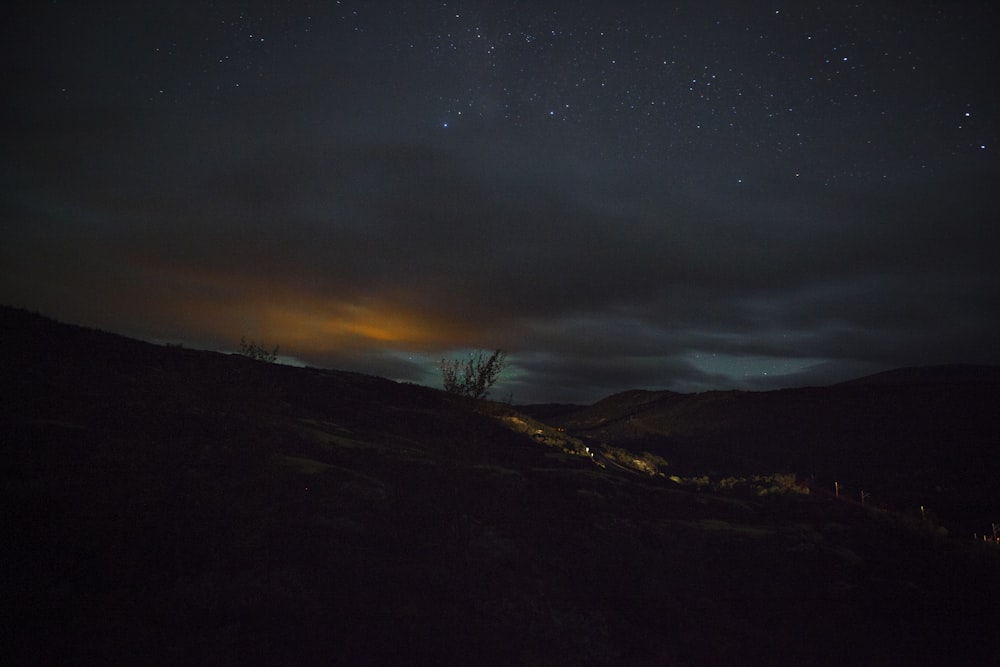 the night sky with stars above a hill